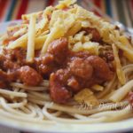 Chili on pasta noodles topped with cheese and crushed corn chips_