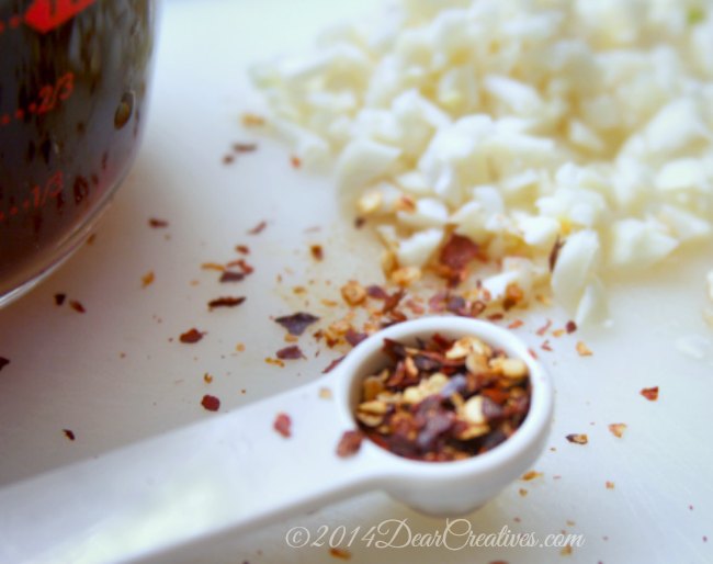Red pepper flakes in a measuring spoon_chopped garlic_soy sauce in a measuring cup_food prep_