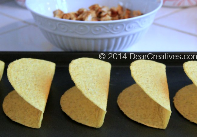 Taco shells on a baking pan_ bowl of chopped chicken_