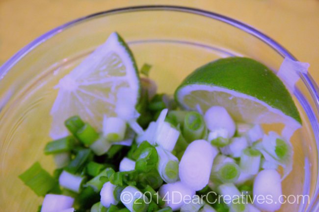 Chicken Tacos fixings chopped green onion and lime wedges in a bowl