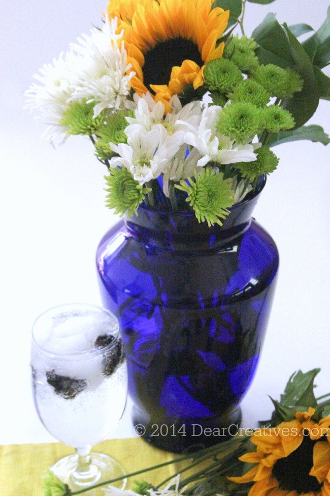 flowers in a vase next to a glass of sparkling water_