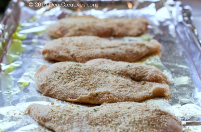 Breaded chicken on a lined cookie sheet ready to bake for oven fried chicken