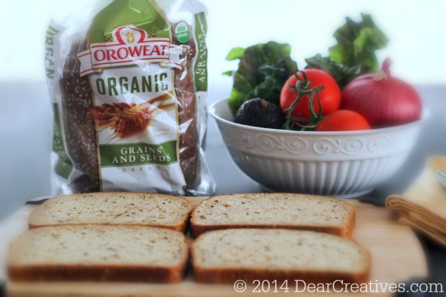 Organic Bread on a cutting board and sandwich veggies in a bowl_
