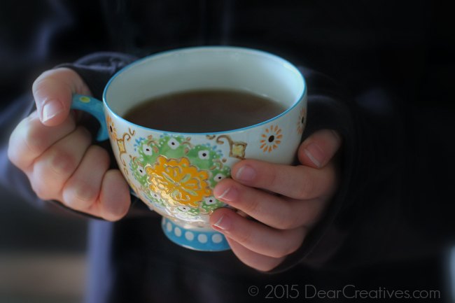 hands holding a cup with green tea