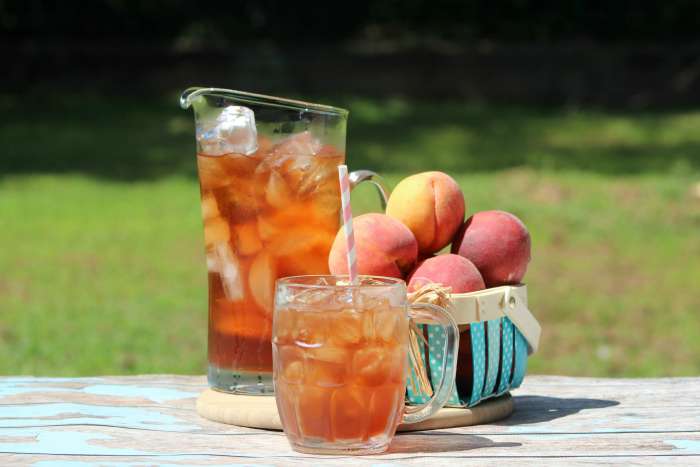 Ice Tea made with peaches. Peaches and Iced Tea in a pitcher and peach iced tea in a glass. Peach iced tea recipe at DearCreatives.com