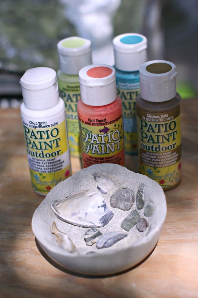 decorative bowl with seashells next to patio paints ready to be painted on the outside of the bowls for decor