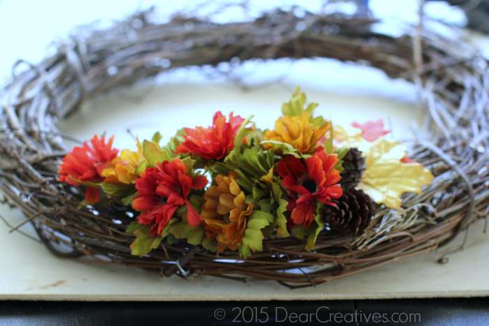 Making floral wreath flowers and pine cones on side of wreath