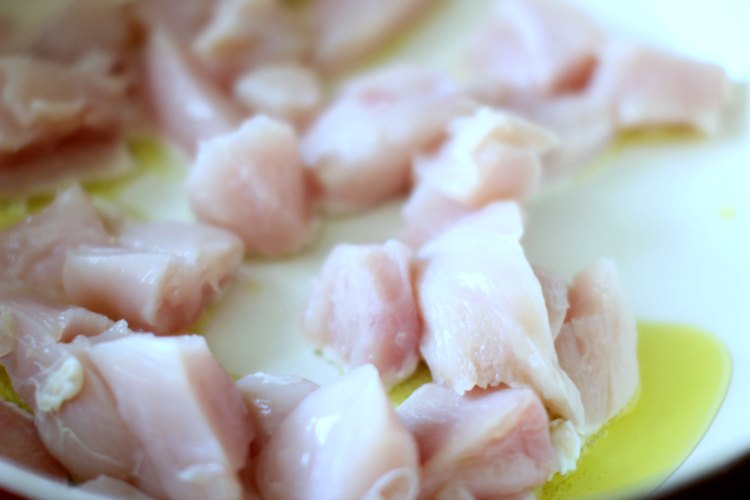 cut cubed chicken for a dinner recipe cooking in a pan