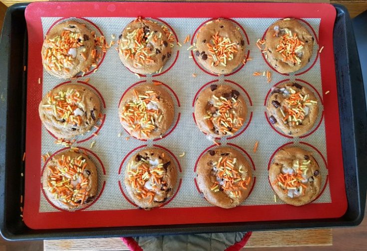 Easy gluten-free chocolate chip Halloween cookies with sprinkles cooling on a parchment-lined sheet pan.