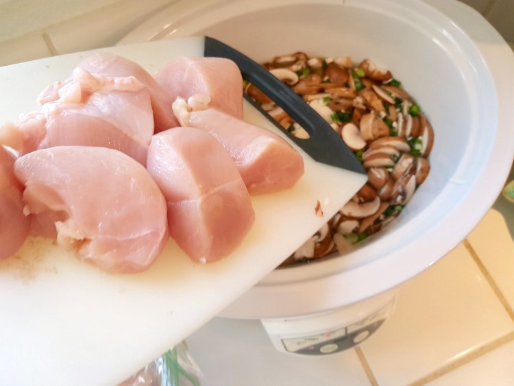 Dumping cut up chicken into the mushrooms, broth to make mushroom soup in the crockpot. See this easy recipe at © 2017 DearCreatives.com