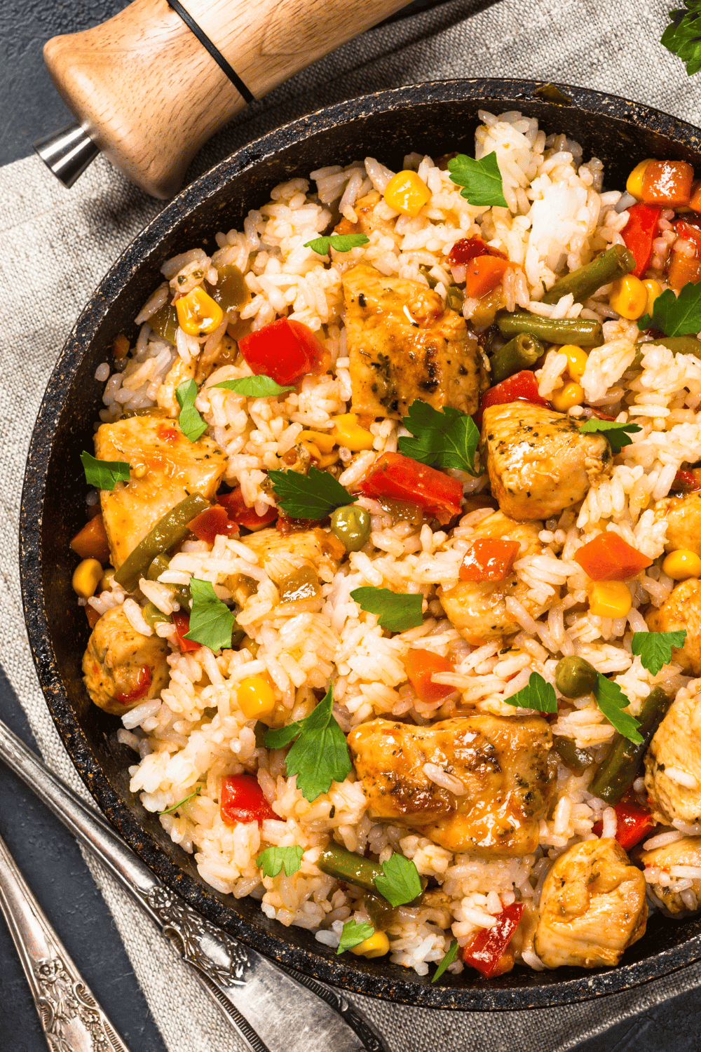 A skillet of one-pot chicken and rice with chicken pieces and colorful vegetables.