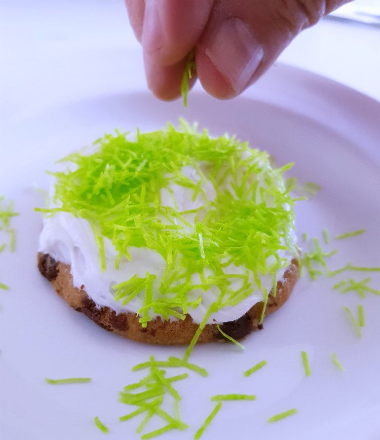 adding edible grasss sprinkles to make a birds nest cookie © 2018 DearCreatives.com