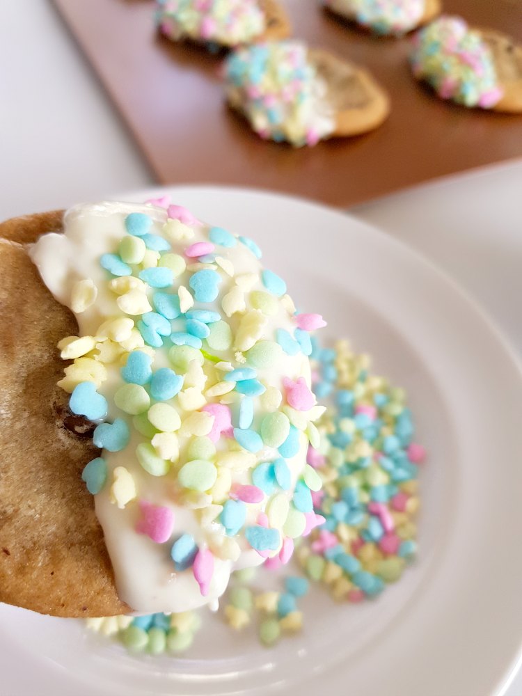 chocolate dipped chocolate chip cookie with melted white chocolate, and Ester bunny sprinkles. See how to make this easy recipe. DearCreatives.com