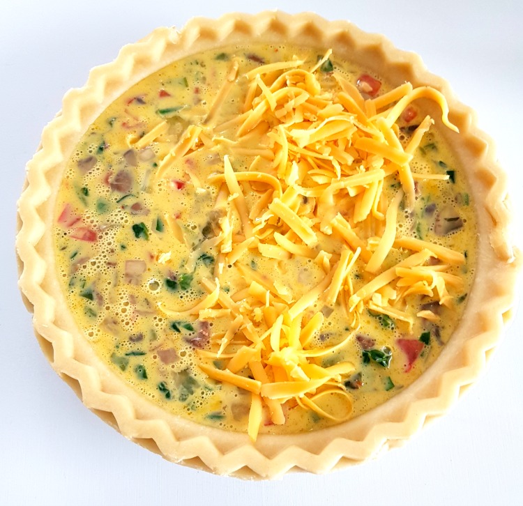 adding cheese to top of cheese quiche ready to be baked in the oven © DearCreatives.com