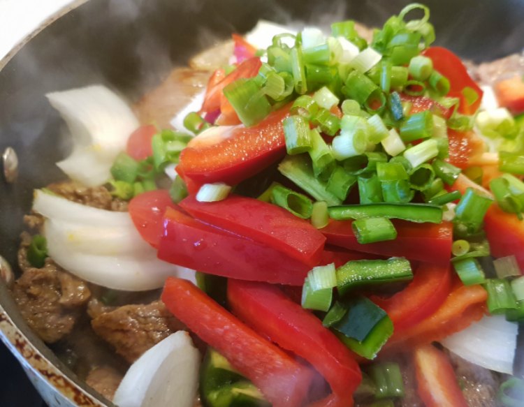 stir fry beef with red bell pepper, onions, jalapeno and green onions cooking in a skillet DearCreatives.com