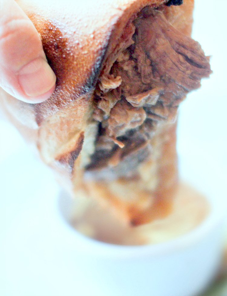 French Dip Sandwiches - holding a beef dip sandwich after dipping it in au jus sauce DearCreatives.com