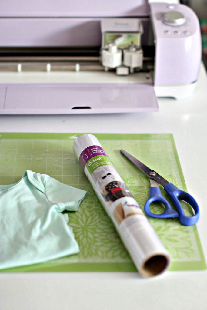 Cricut cutting machine, iron on material, baby onesie, scissors, and cutting mat to make iron on onesies DearCreatives.com