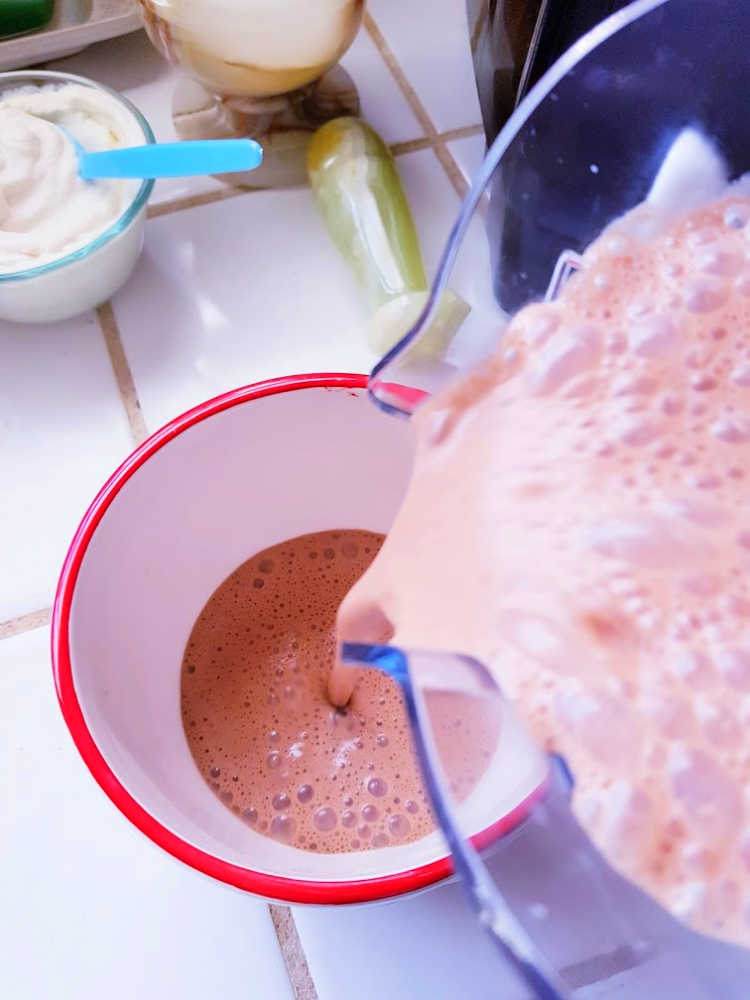 Pouring hot chocolate from a Vitamix blender into a cup. Dearcreatives.com