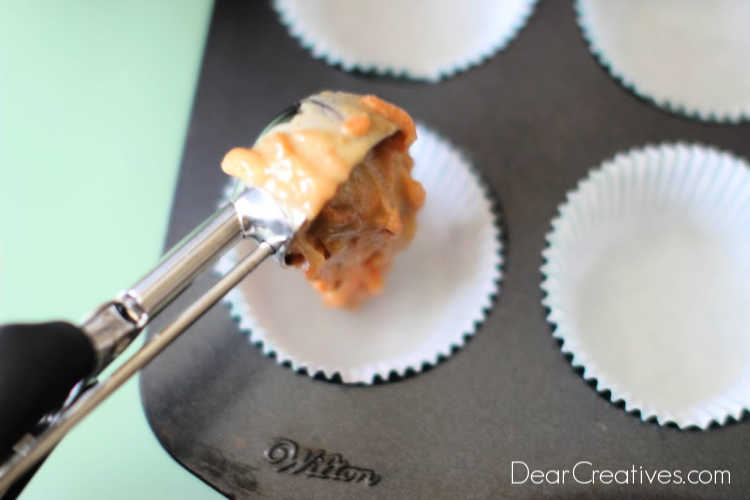 Scooping cupcake batter into a lined cupcake pan for to bake carrot cake cupcakes. DearCreatives.com