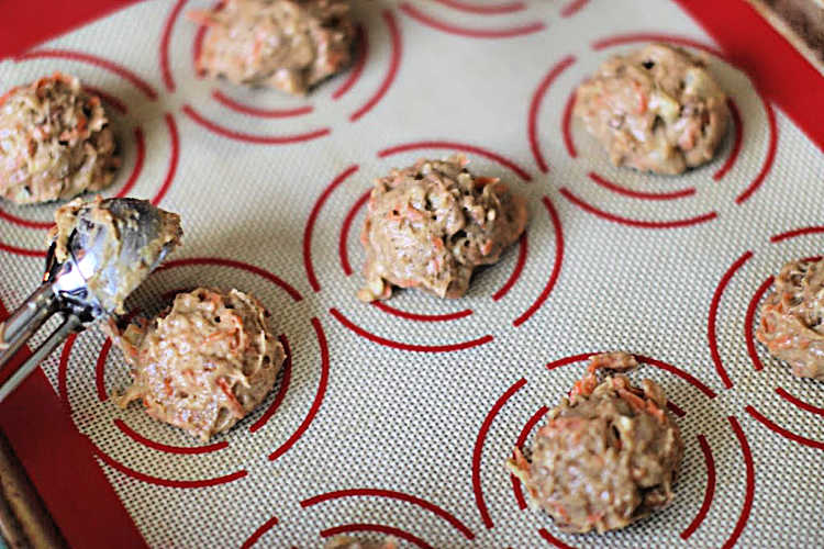 Scooping carrot cake cookie dough onto the lined baking sheet. DearCreatives.com