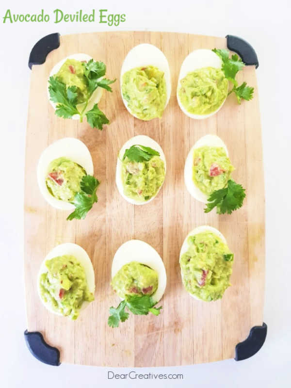 Guacamole deviled eggs on a cutting board ready to serve or store. This is an easy appetizer recipe to make with your hard boiled eggs. You will love this appetizer recipe for parties, brunch, Easter celebrations, Cinco de Mayo celebrations and more. Grab the recipe at DearCreatives.com