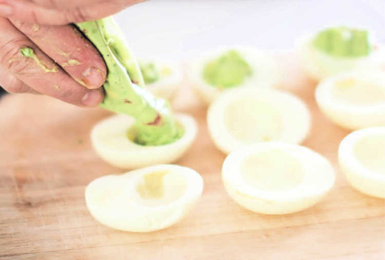 piping avocado deviled eggs - guacamole deviled eggs into the cooked egg with the yolk removed. © 2019 DearCreatives.com