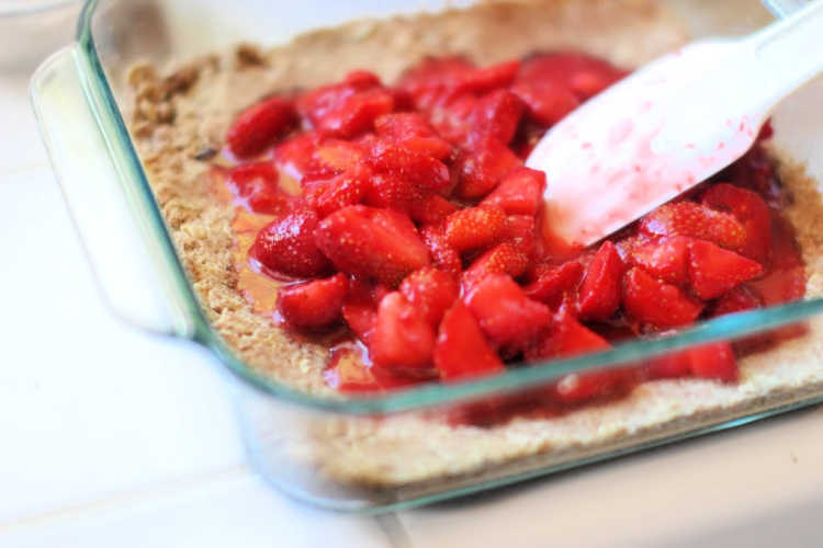 Spreading a macerated strawberries to the top of the strawberry bars crust. DearCreatives.com