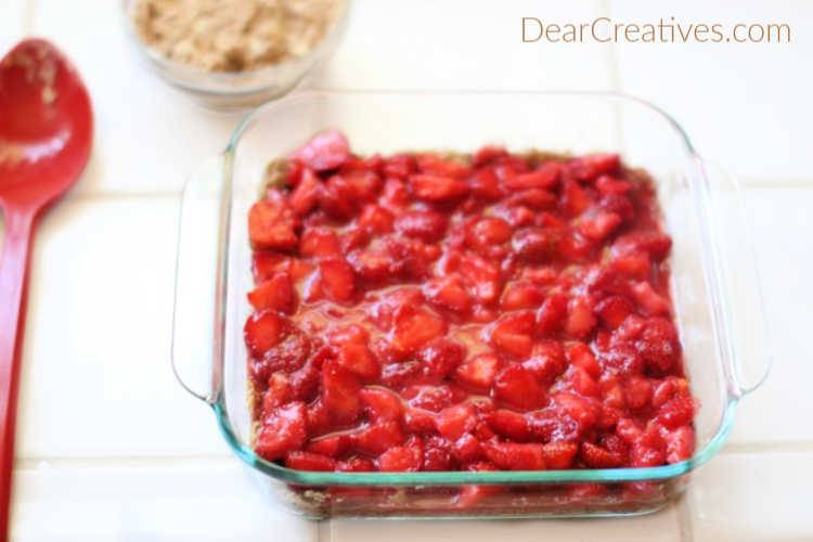 Spreading strawberries evenly across the top of the crust for Strawberry Oatmeal Bars DearCreatives.com