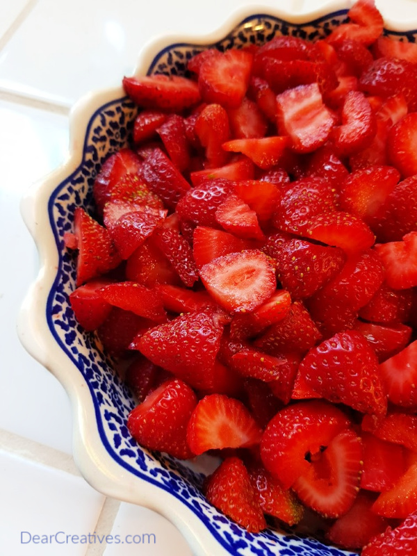 Fresh cut up strawberries in a pie dish ready to have sugar sprinkled on them to make strawberry tarts. Strawberry tart recipe at DearCreatives.com