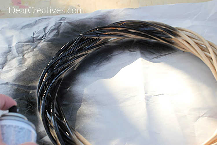Beginning to paint a wreath black to make a Halloween Eyeball Wreath (painting the wreath is an optional step) © DearCreatives.com