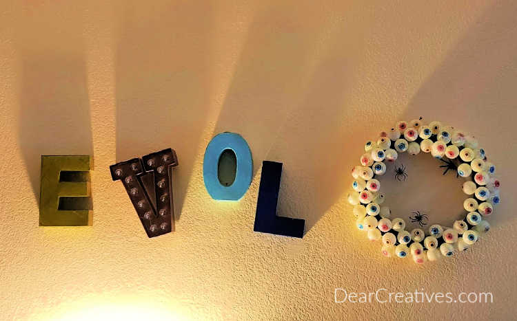 Eyeball Wreath Hanging on the living room wall. Love sign turned to say evil. See how to make an Eyeball Wreath for Halloween or a party at ©DearCreatives.com