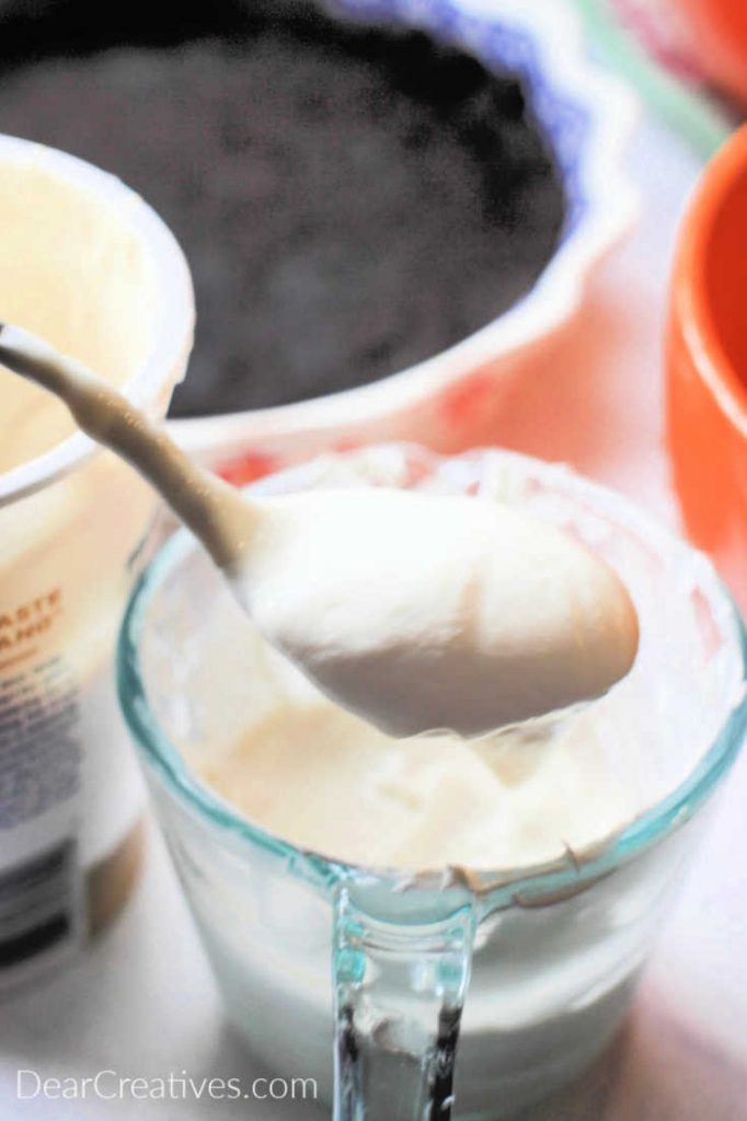 Adding Greek style yogurt to a measuring cup to make the topping for a Chocolate Cream Pie © DearCreatives.com