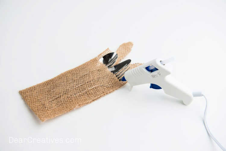 Using hot glue to glue the burlap bunny utensil holder - DIY silverware holder at DearCreatives.com