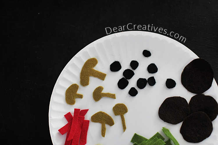 Food shapes cut from felt to make a felt pizza - mushrooms, pepperoni, olives, bell peppers, onions... DearCreatives.com