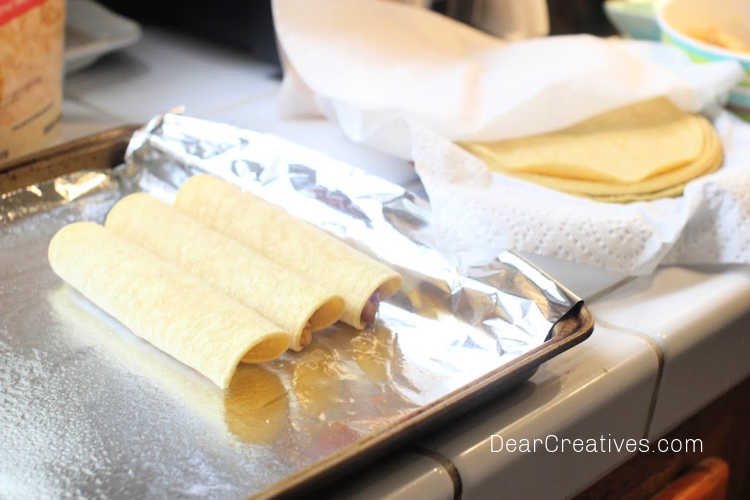 How to make Chicken Taquitos and bake them in the oven - facing the rolled tortillas, seams side down-©DearCreatives.com