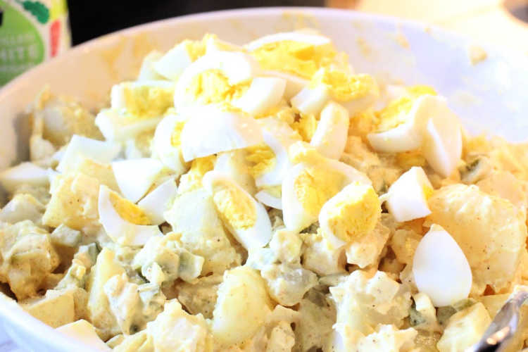 adding the hard boiled eggs and potatoes to fold into the potato salad. Grab this side dish with potatoes recipe at DearCreatives.com