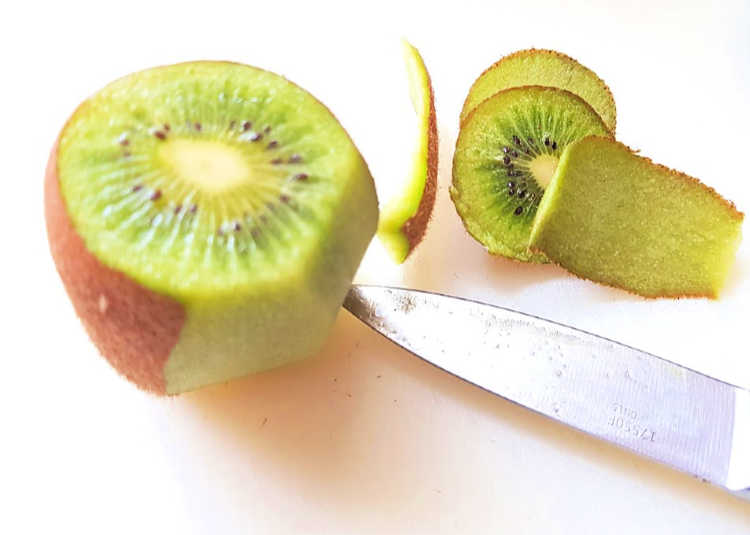 slicing the skin off a kiwi for a strawberry kiwi smoothie - DearCreatives.com