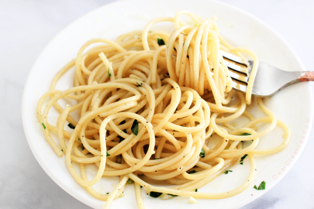 A plate of spaghetti with garlic and olive oil ready to be eaten. 10 minutes and easy - spaghetti with garlic at DearCreatives.com