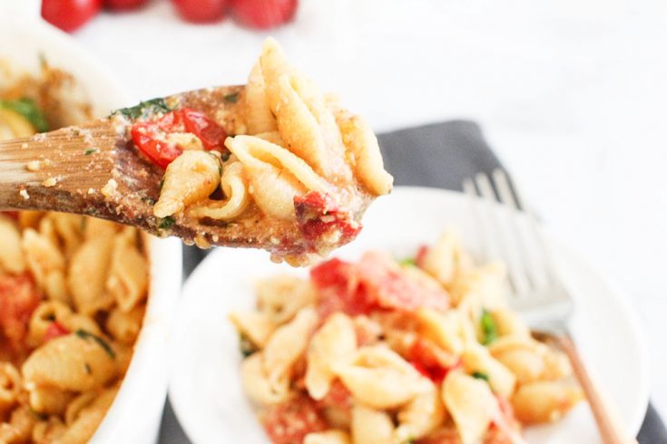 Baked feta pasta with tomatoes being served onto a plate - Get the recipe for feta pasta at © DearCreatives.com