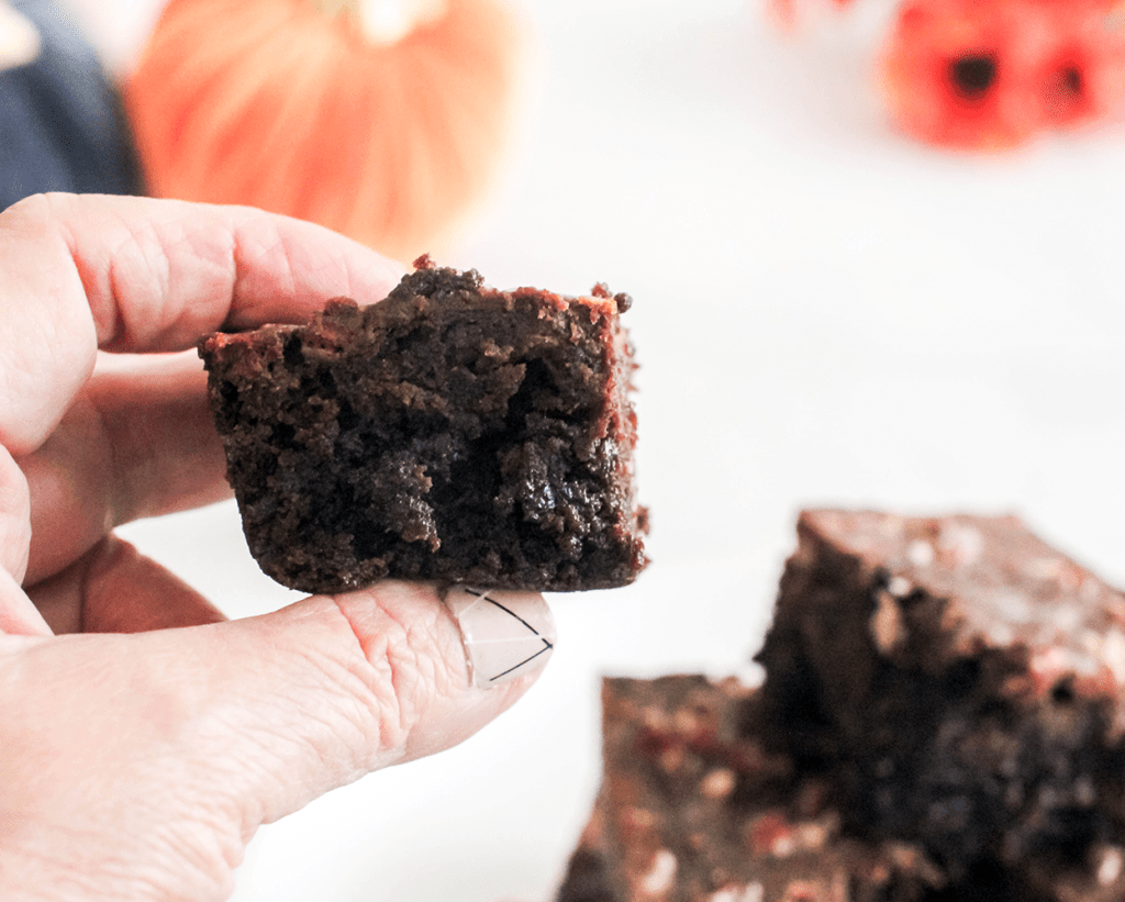 Holding a cooled, baked pumpkin brownie. These brownies with pumpkin are easy to make and delicious © DearCreatives.com