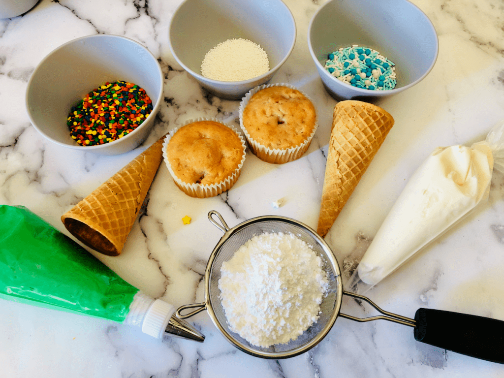 Cooled cupcakes, sugar cones, green and white frosting, powdered sugar and sprinkles for making cupcake toppers for the holidays - Instructions at DearCreatives.com