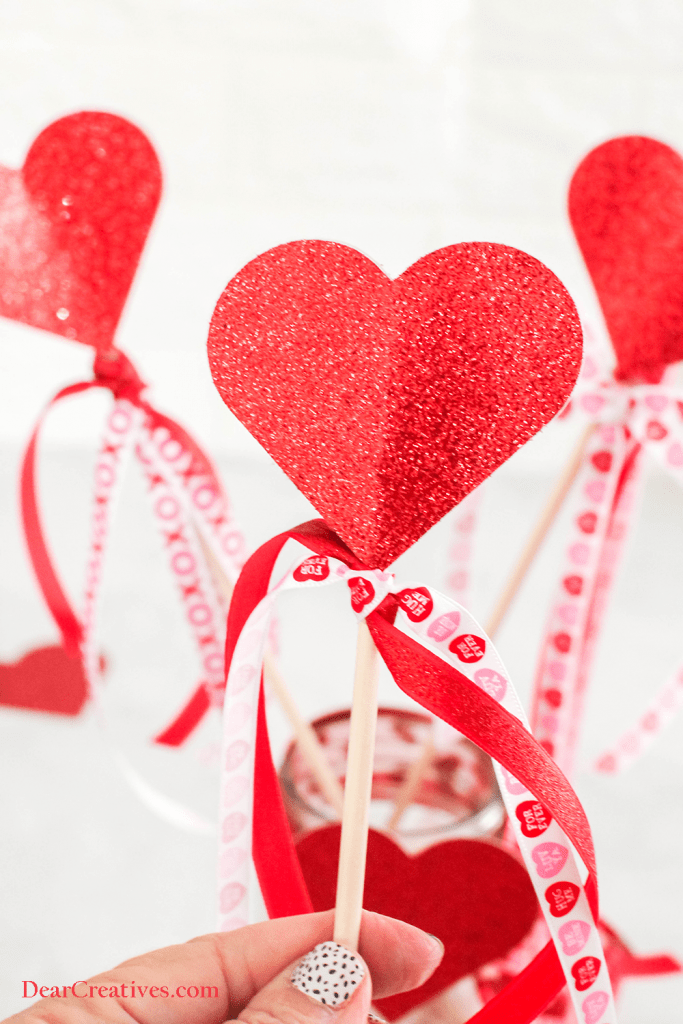 Close up holding a Heart Wand made with glitter cardstock, dowel and ribbons. (DIY includes a Printable Heart Template) ©2022 DearCreatives.com