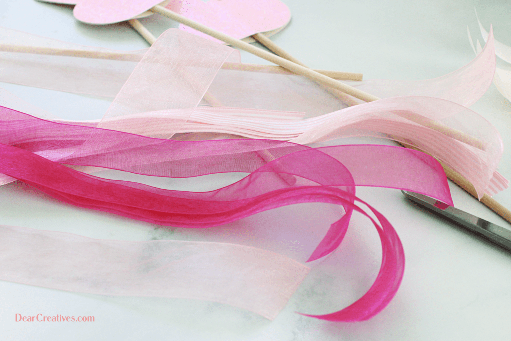 Supplies for bunny craft - pretty ribbons, bunny heads cut out using glitter cardstock, dowels, scissors...© DearCreatives.com