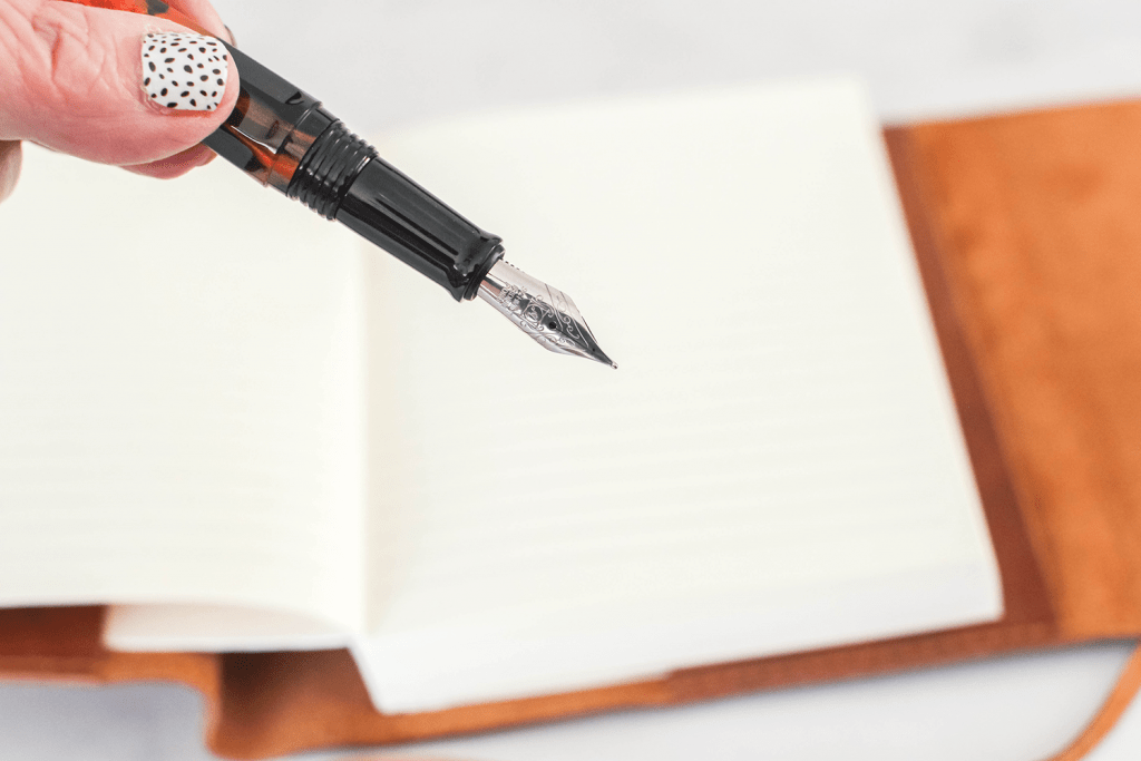 holding an fountain pen, ink pen getting ready to write in a journal © DearCreatives.com