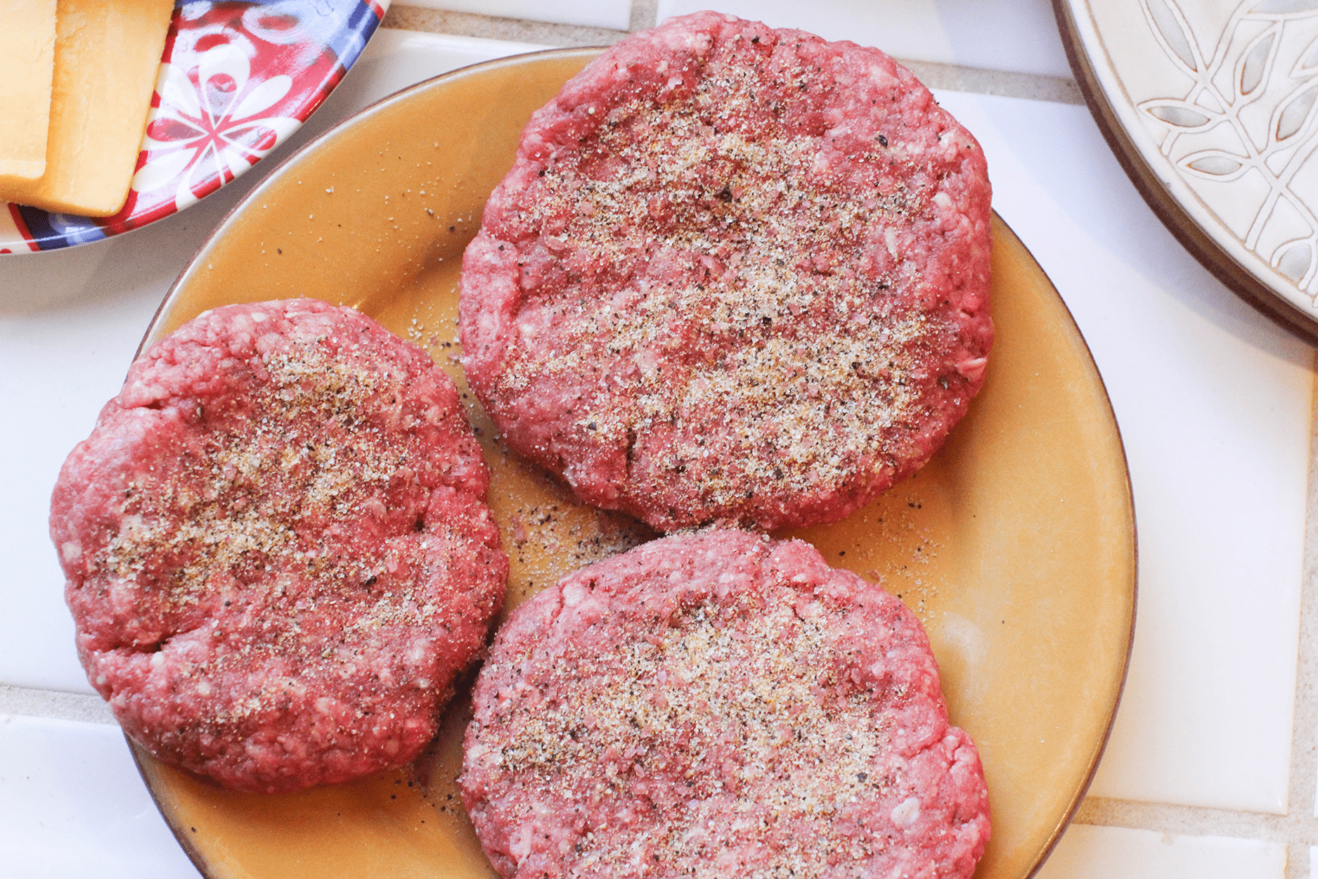 Seasoned hamburgers on a plate ready to be grilled - recipe for burgers - grilled burger seasoning ©2022 DearCreatives.com