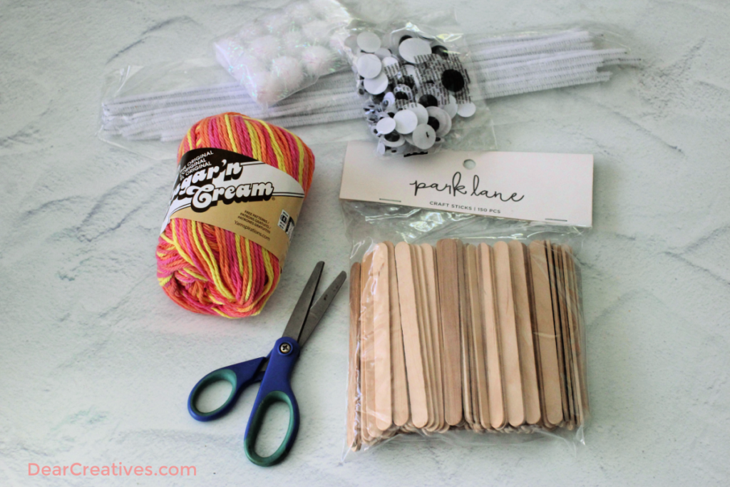 supplies for making Popsicle stick butterflies - craft sticks, yarn, pom poms for crafts, pipe cleaner... See the tutorial with images and finished craft at DearCreatives.com