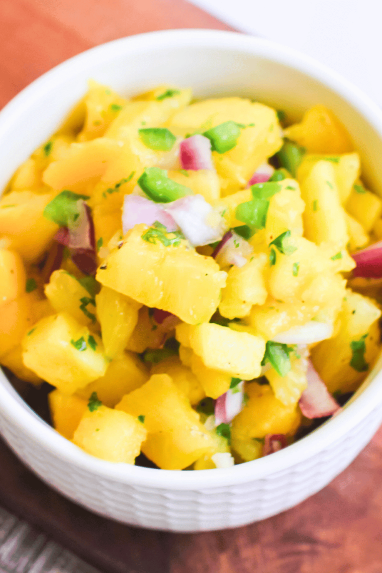 Close-up of a rustic bowl filled with chunky, vibrant pineapple mango salsa, topped with fresh cilantro, ready to be scooped with tortilla chips.