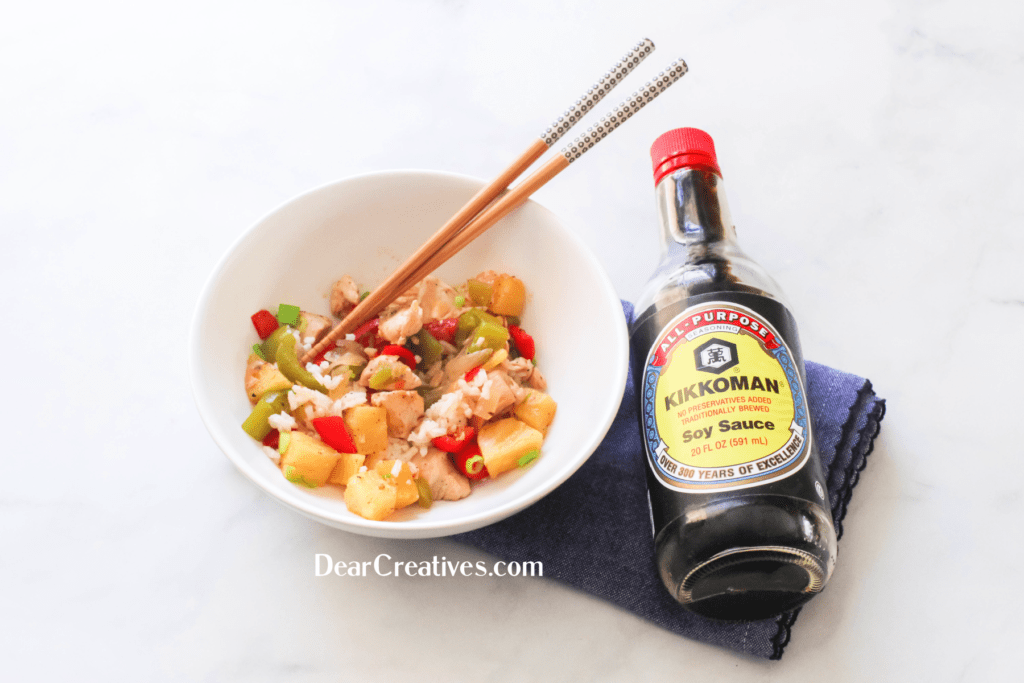 Chicken Stir Fry With Pineapple In a Bowl With Rice. And Soy Sauce next to it. Print the recipe at ©2022 DearCreatives.com