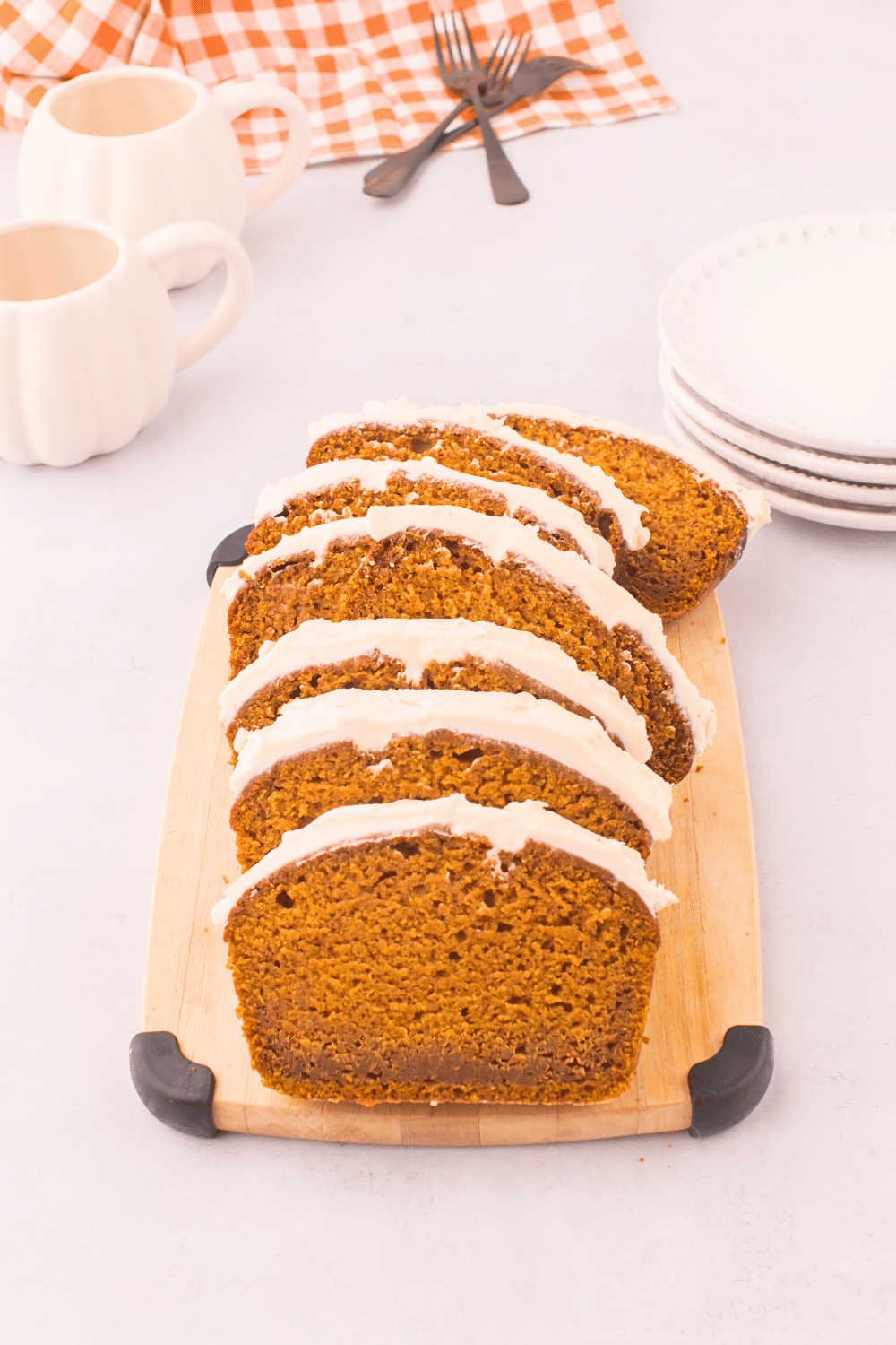 Pumpkin Bread Topped With a Cream Cheese Frosting and Sliced on a cutting board ready to be served. Print the recipe at DearCreatives.com