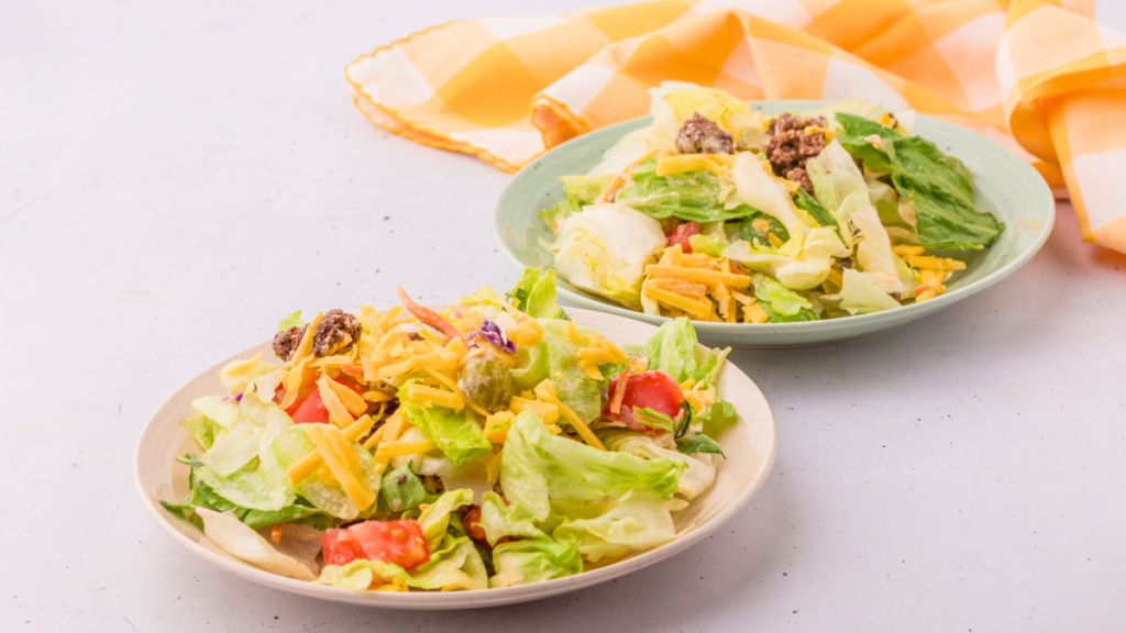 Big Mac Salad on plates ready to be served. Extra dressing reserved to add as needed or desired Get the recipe for this cheeseburger salad and dressing at DearCreatives.com